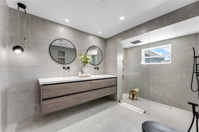 bathroom with a walk in shower, double vanity, and tile walls