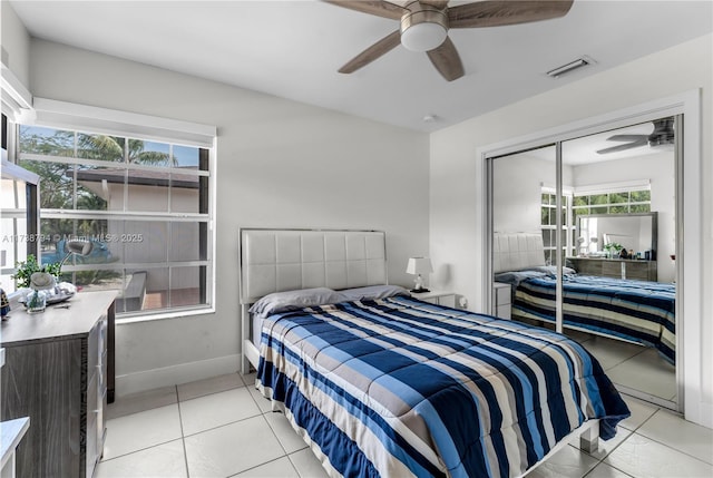 bedroom featuring light tile patterned flooring, a ceiling fan, visible vents, baseboards, and a closet