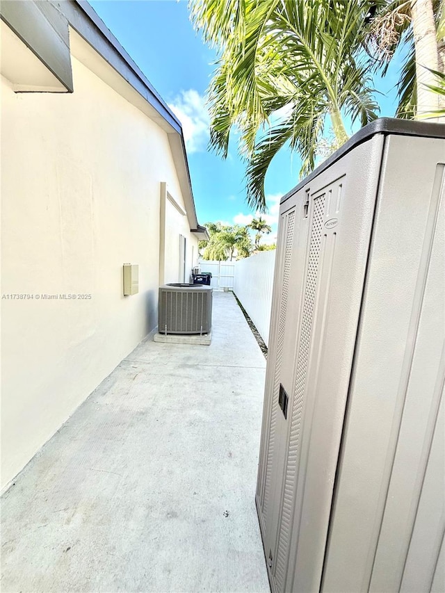 view of property exterior with central AC, fence, and a patio