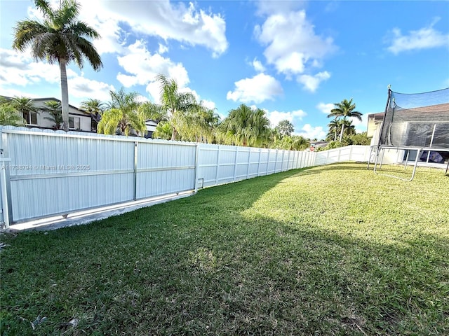 view of yard with a trampoline and a fenced backyard