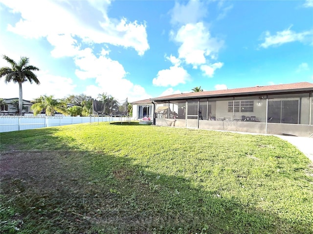 rear view of house featuring a lawn, fence, and a sunroom