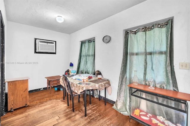 dining space with hardwood / wood-style flooring and a wall unit AC