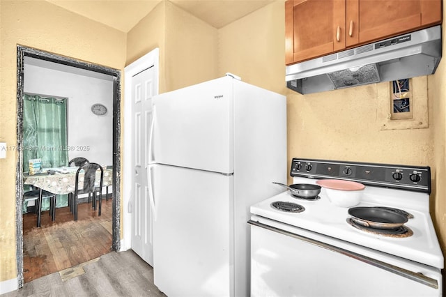 kitchen with white appliances and light hardwood / wood-style flooring