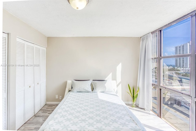 bedroom featuring expansive windows, a closet, a textured ceiling, and light hardwood / wood-style flooring