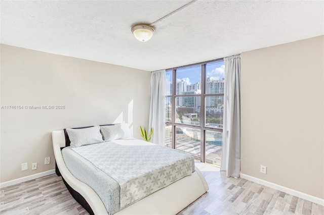 bedroom featuring floor to ceiling windows, light hardwood / wood-style flooring, and a textured ceiling