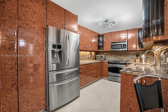 kitchen with brown cabinetry, appliances with stainless steel finishes, decorative backsplash, and a sink