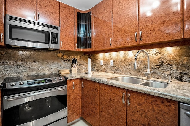 kitchen with stainless steel appliances, tasteful backsplash, brown cabinetry, and a sink