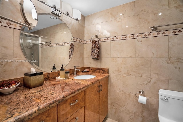 bathroom with tile walls, vanity, toilet, and walk in shower