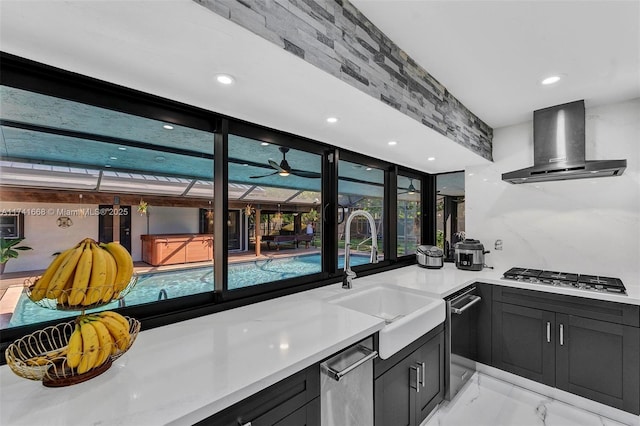 kitchen featuring wall chimney exhaust hood, marble finish floor, light countertops, stainless steel gas cooktop, and a sink