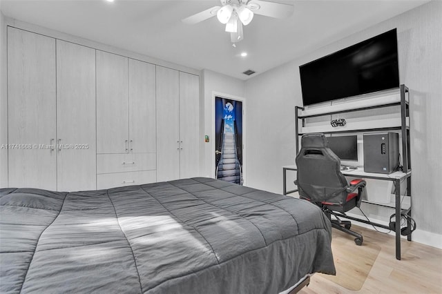 bedroom featuring a closet, wood finished floors, visible vents, and a ceiling fan