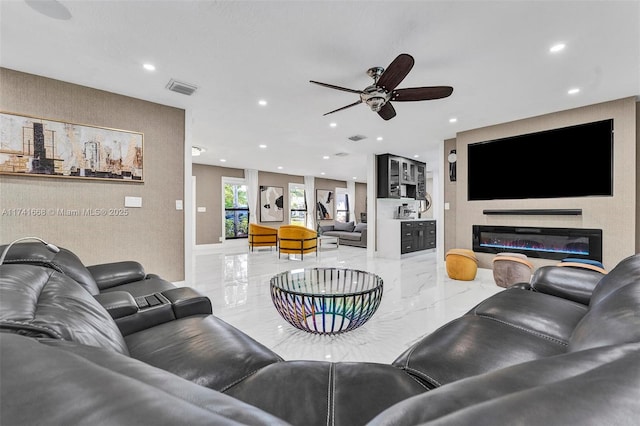 living area with ceiling fan, recessed lighting, visible vents, marble finish floor, and a glass covered fireplace