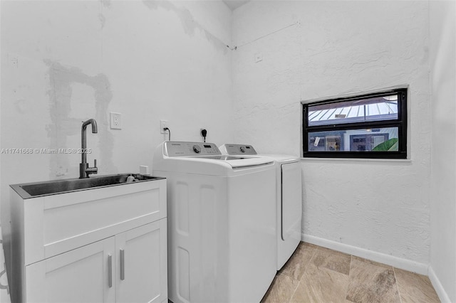 laundry area featuring washer and clothes dryer, a sink, cabinet space, and baseboards