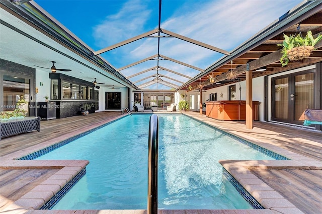 pool featuring glass enclosure, ceiling fan, a hot tub, and a patio