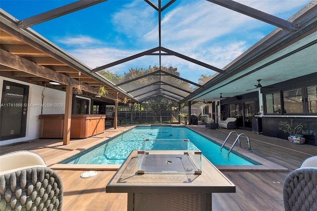 view of swimming pool featuring ceiling fan, a lanai, fence, a fenced in pool, and a hot tub