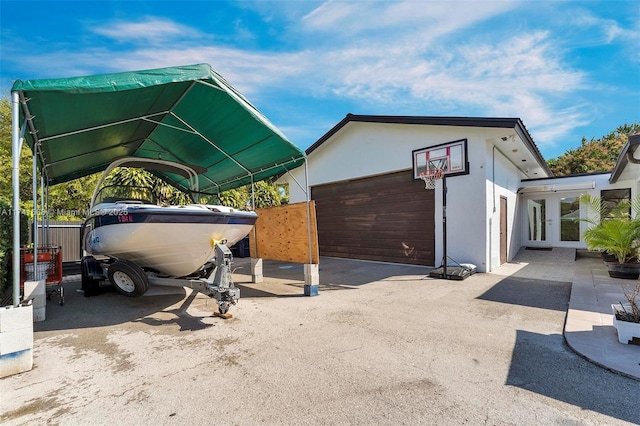 view of parking with a garage, french doors, fence, and a carport