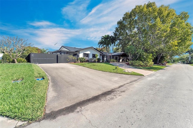 single story home with a front yard, a gate, metal roof, fence, and driveway