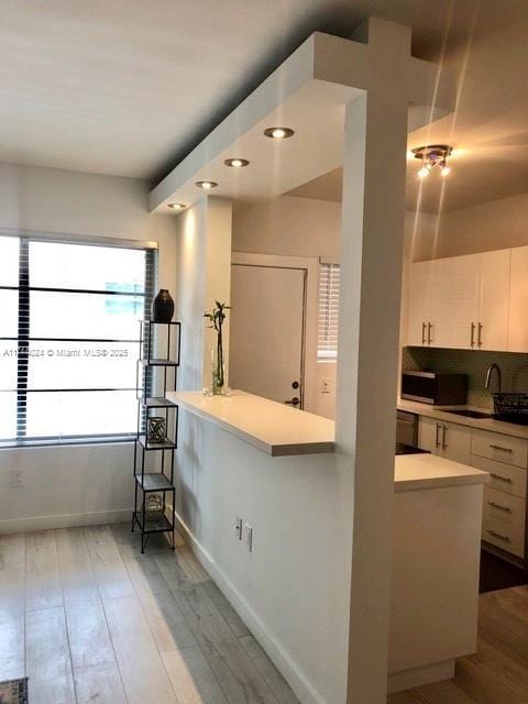 kitchen featuring sink, white cabinetry, a kitchen breakfast bar, kitchen peninsula, and hardwood / wood-style floors