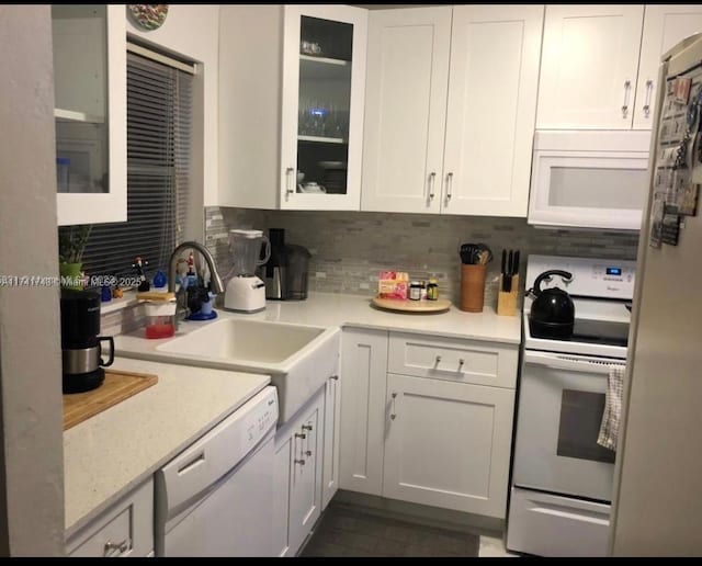 kitchen with white cabinetry, sink, decorative backsplash, light stone countertops, and white appliances