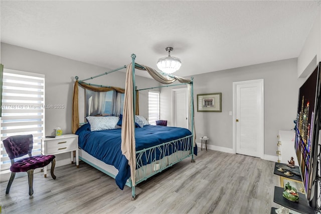 bedroom featuring multiple windows, hardwood / wood-style floors, and a textured ceiling