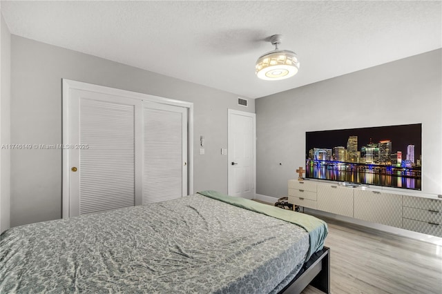 bedroom with hardwood / wood-style floors, a closet, and a textured ceiling