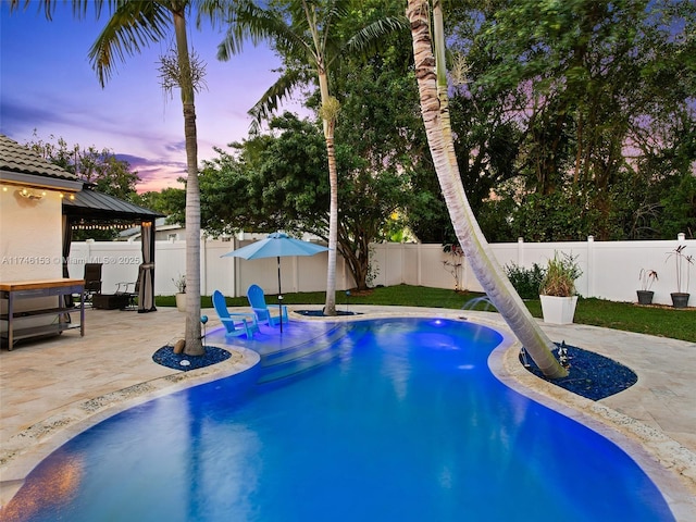 pool at dusk with a gazebo and a patio