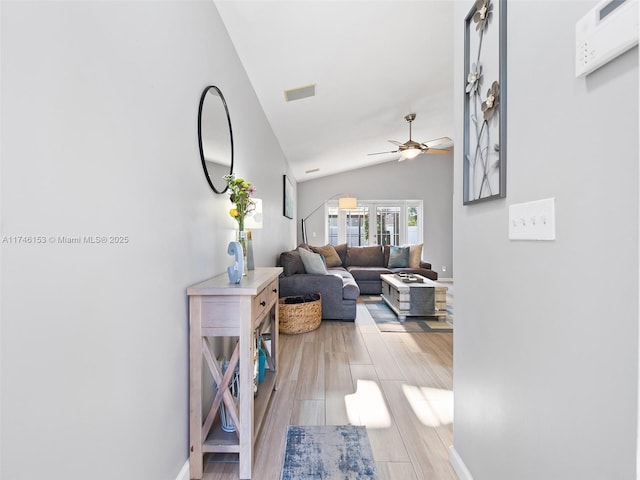 hallway with vaulted ceiling and light wood-type flooring