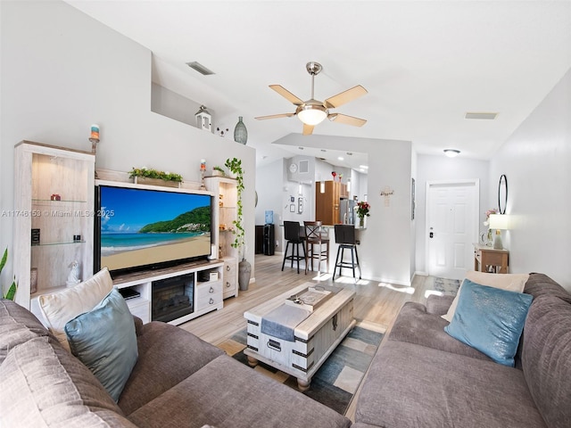 living room featuring vaulted ceiling, light hardwood / wood-style floors, and ceiling fan