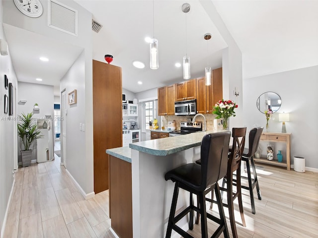 kitchen with pendant lighting, a kitchen breakfast bar, decorative backsplash, kitchen peninsula, and stainless steel appliances