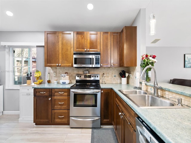 kitchen featuring tasteful backsplash, appliances with stainless steel finishes, decorative light fixtures, and sink