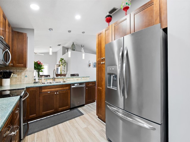 kitchen featuring sink, backsplash, hanging light fixtures, stainless steel appliances, and kitchen peninsula