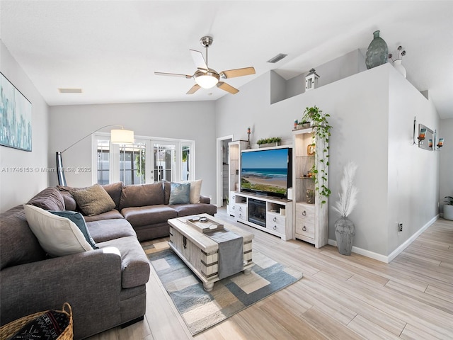 living room with vaulted ceiling, ceiling fan, light wood-type flooring, and french doors