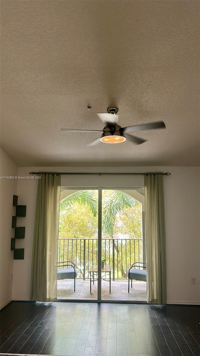 unfurnished room with dark wood-style floors, a ceiling fan, a wealth of natural light, and a textured ceiling