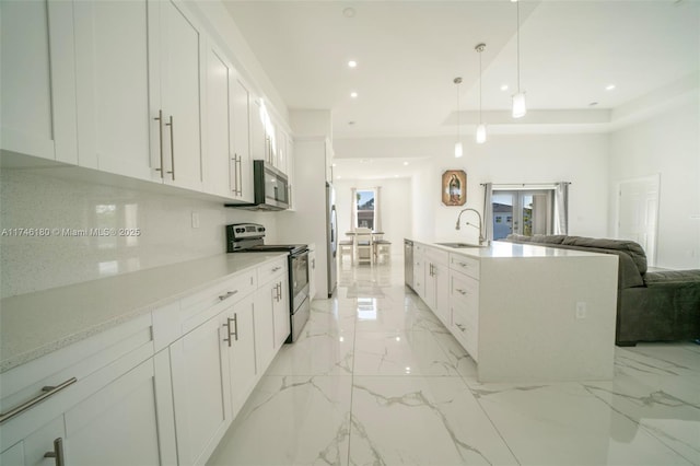 kitchen with sink, white cabinetry, decorative light fixtures, a center island with sink, and appliances with stainless steel finishes