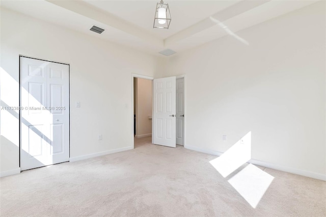 unfurnished bedroom with light colored carpet and a raised ceiling