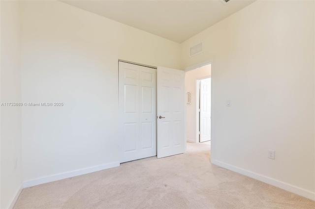 unfurnished bedroom with light colored carpet and a closet