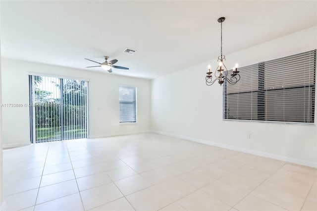 tiled spare room featuring ceiling fan with notable chandelier