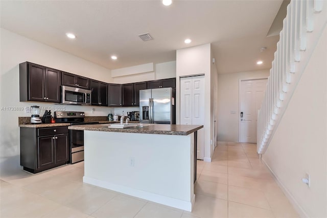 kitchen featuring light tile patterned flooring, dark brown cabinetry, sink, a kitchen island, and stainless steel appliances