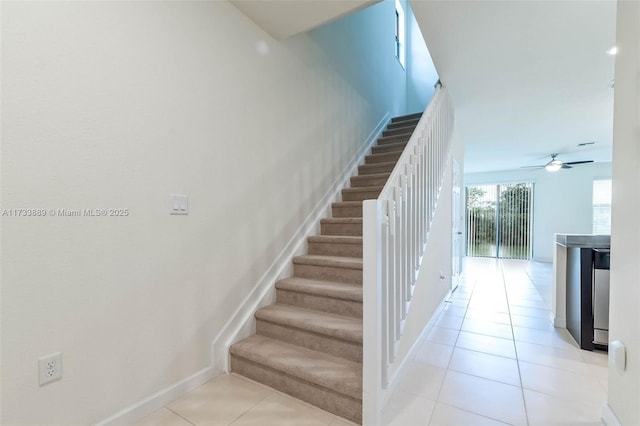 stairway featuring tile patterned flooring and ceiling fan