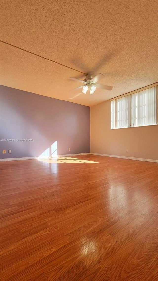 empty room featuring ceiling fan, hardwood / wood-style flooring, and a textured ceiling