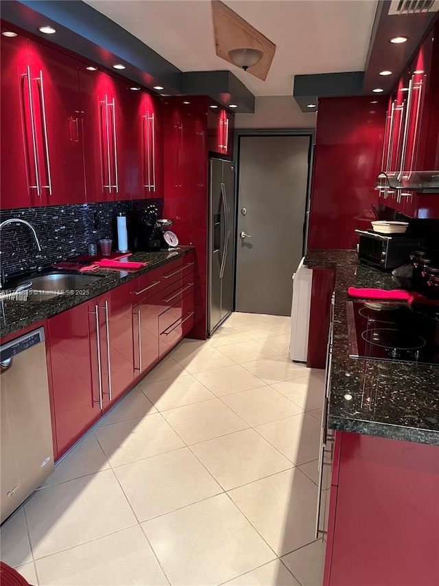 kitchen featuring dark stone countertops, sink, light tile patterned floors, and appliances with stainless steel finishes