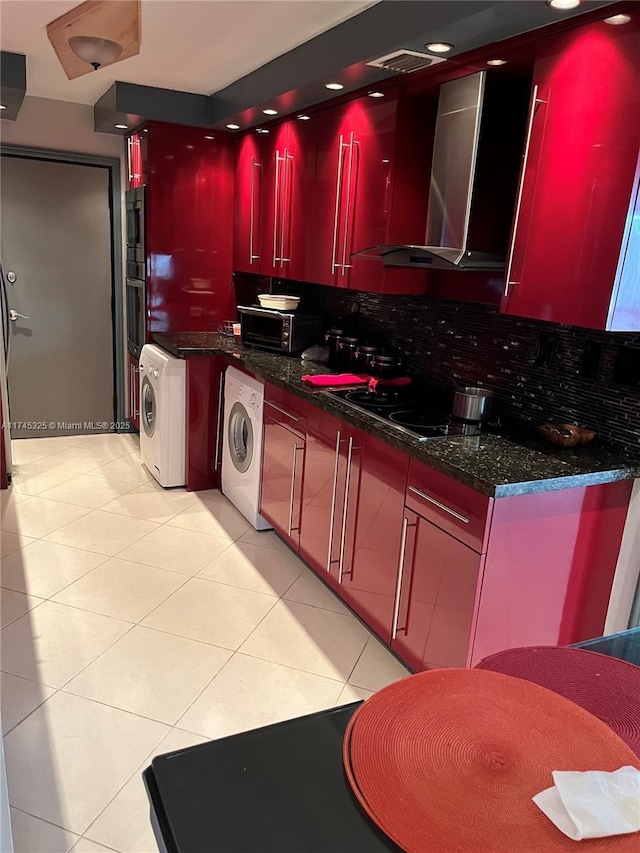 kitchen with washer / clothes dryer, cooktop, dark stone counters, and wall chimney exhaust hood