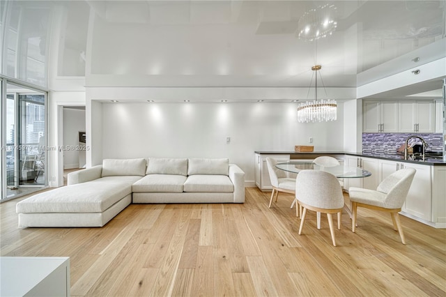 living room with a towering ceiling, sink, and light hardwood / wood-style flooring