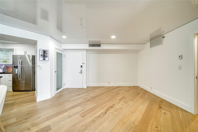 empty room with light hardwood / wood-style flooring and a high ceiling