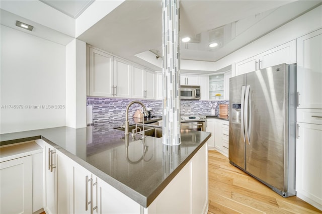 kitchen with light hardwood / wood-style flooring, kitchen peninsula, white cabinets, and appliances with stainless steel finishes