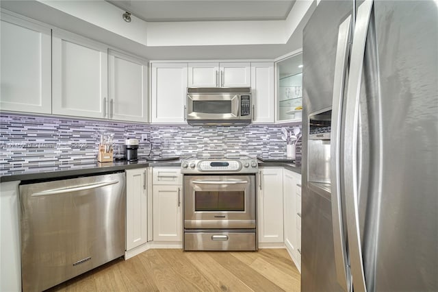 kitchen featuring decorative backsplash, light hardwood / wood-style floors, white cabinets, and appliances with stainless steel finishes