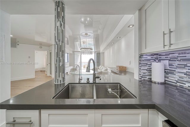 kitchen with sink, white cabinets, light hardwood / wood-style floors, and decorative backsplash