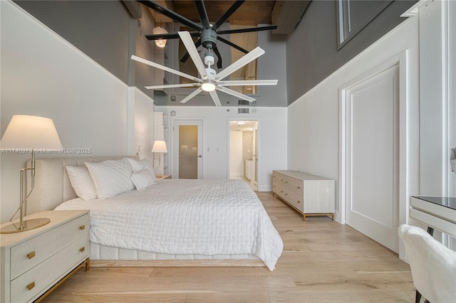 bedroom featuring connected bathroom, light hardwood / wood-style floors, and a high ceiling