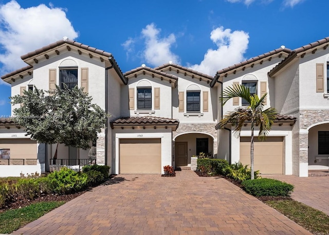 mediterranean / spanish home with a garage, decorative driveway, a tile roof, and stucco siding