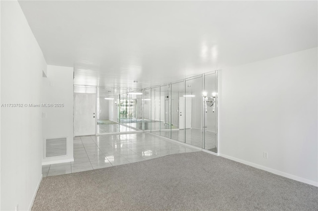 empty room with baseboards, visible vents, and carpet flooring