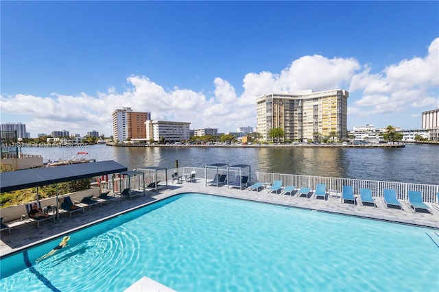 pool with a water view, fence, and a city view